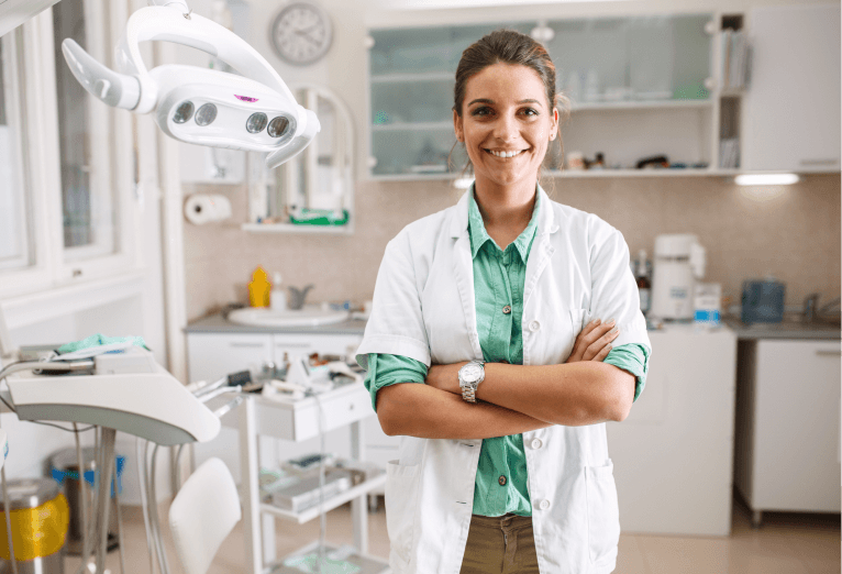 Mujer dentista sonriente en la clínica con los brazos cruzados.